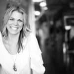 Turning Dreams Into Reality With Megan Stone black and white photo of a blonde woman smiling in a white blouse with a necklace