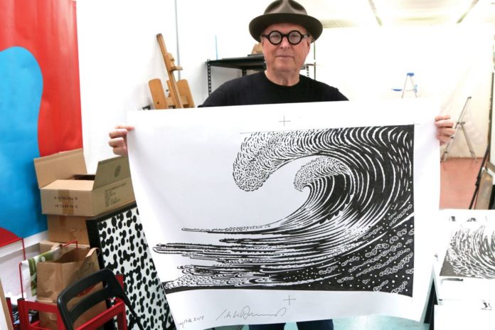 JVH Man in a hat and glasses holding up black and white wave artwork