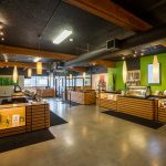 Green-Theory: Concrete, Bamboo & All-Natural Comfort interior of cannabis dispensary with green walls and wood display counters