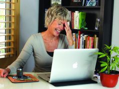 Spotlight On “Marijuana Straight Talk” Show middle age married woman laughing over laptop with cannabis plant in foreground