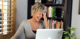 Spotlight On “Marijuana Straight Talk” Show middle age married woman laughing over laptop with cannabis plant in foreground