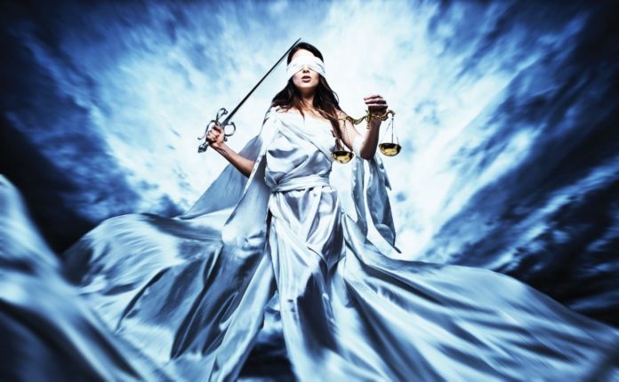 blindfolded woman in long lady justice white robes with sword and scales