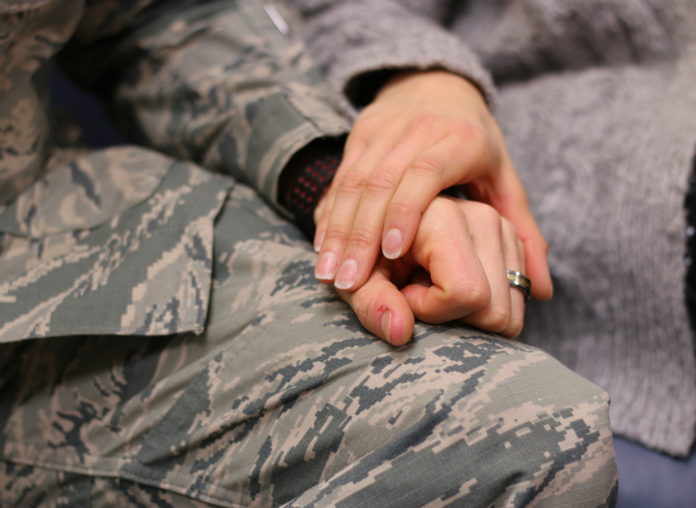 military man wearing a ring holding hands with loving female