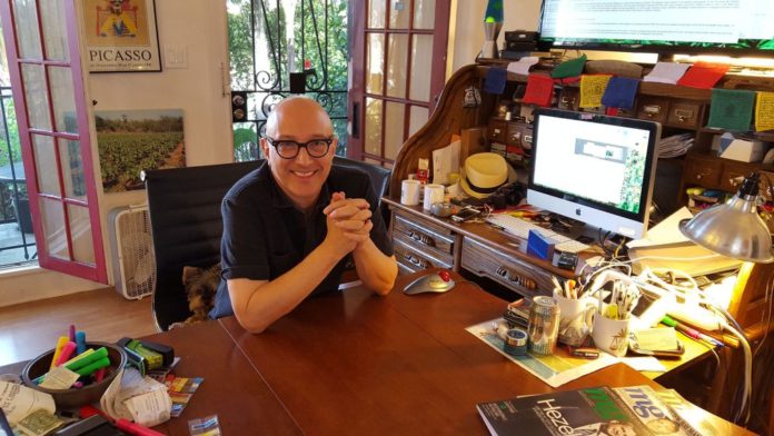 Stewart Richlin bald man with glasses smiling next to his dog at his home office