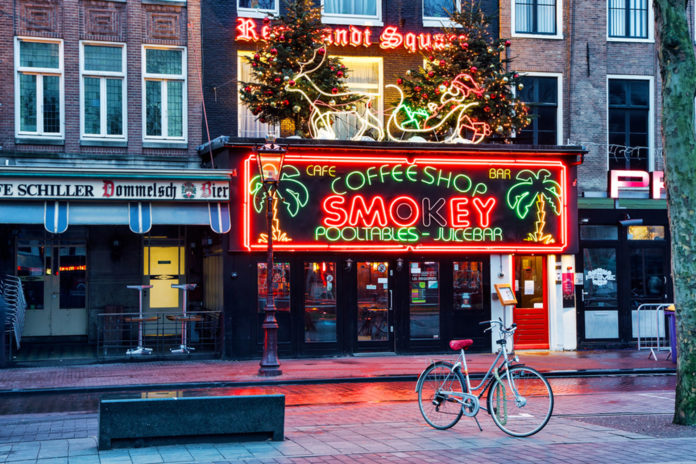 smokey coffeeshop storefront with bright red lights in amsterdamn
