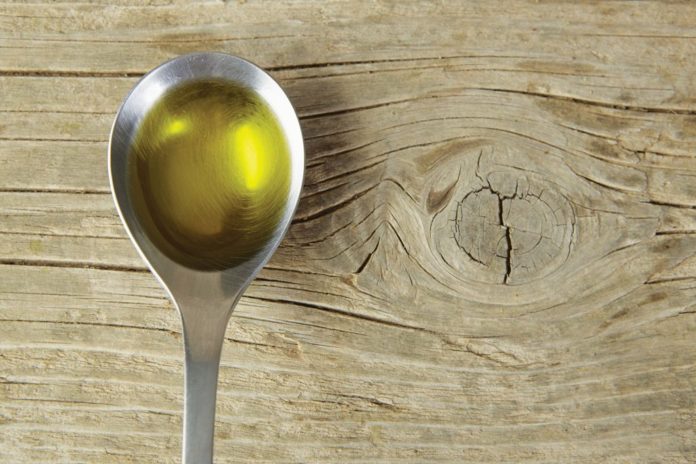 cannabis olive oil in silver spoon over wood table