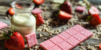 Get Lucky With These 7 Cannabis Valentine’s Day Gifts pink cannabis-infused chocolate bars on a table with strawberries and cream