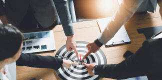 High Finance: What Makes a Good Acquisition Target? Executives pointing to acquisition target by sutadimages mg Magazine