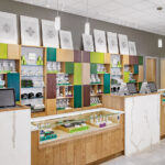 A Closer Look at Visual Merchandising Genius a dispensary counter with light brown and white furniture and splashes of teal and lime green