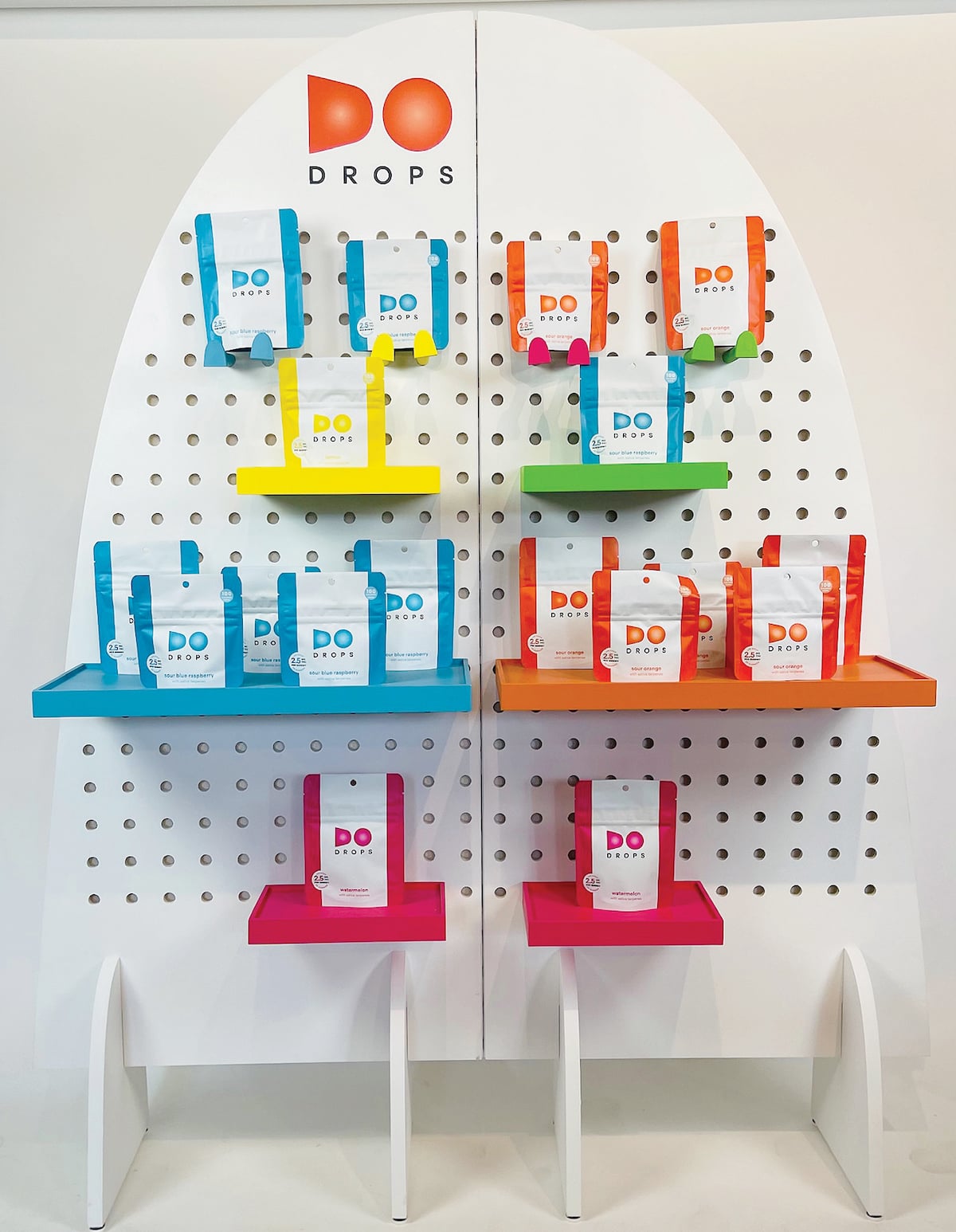 a wall display of Drop cannabis products in little blue orange and pink bags