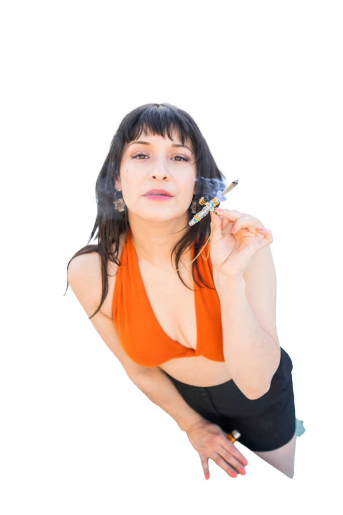 a photo of a woman with black long hair with short bangs wearing an orange bralette and black shorts smoking a joint in an intricate glass filter tip