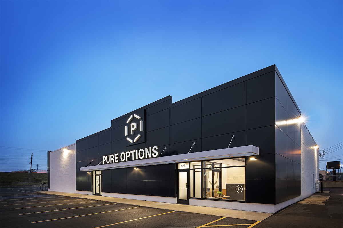 outside a pure options dispensary at dusk the building is all black with pure options in white on the outside of the building 