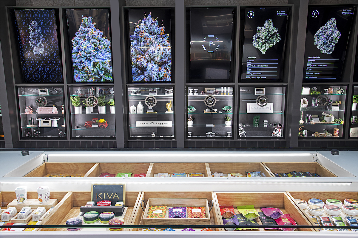 a display case filled with colorful cannabis products and images of magnified buds in the background