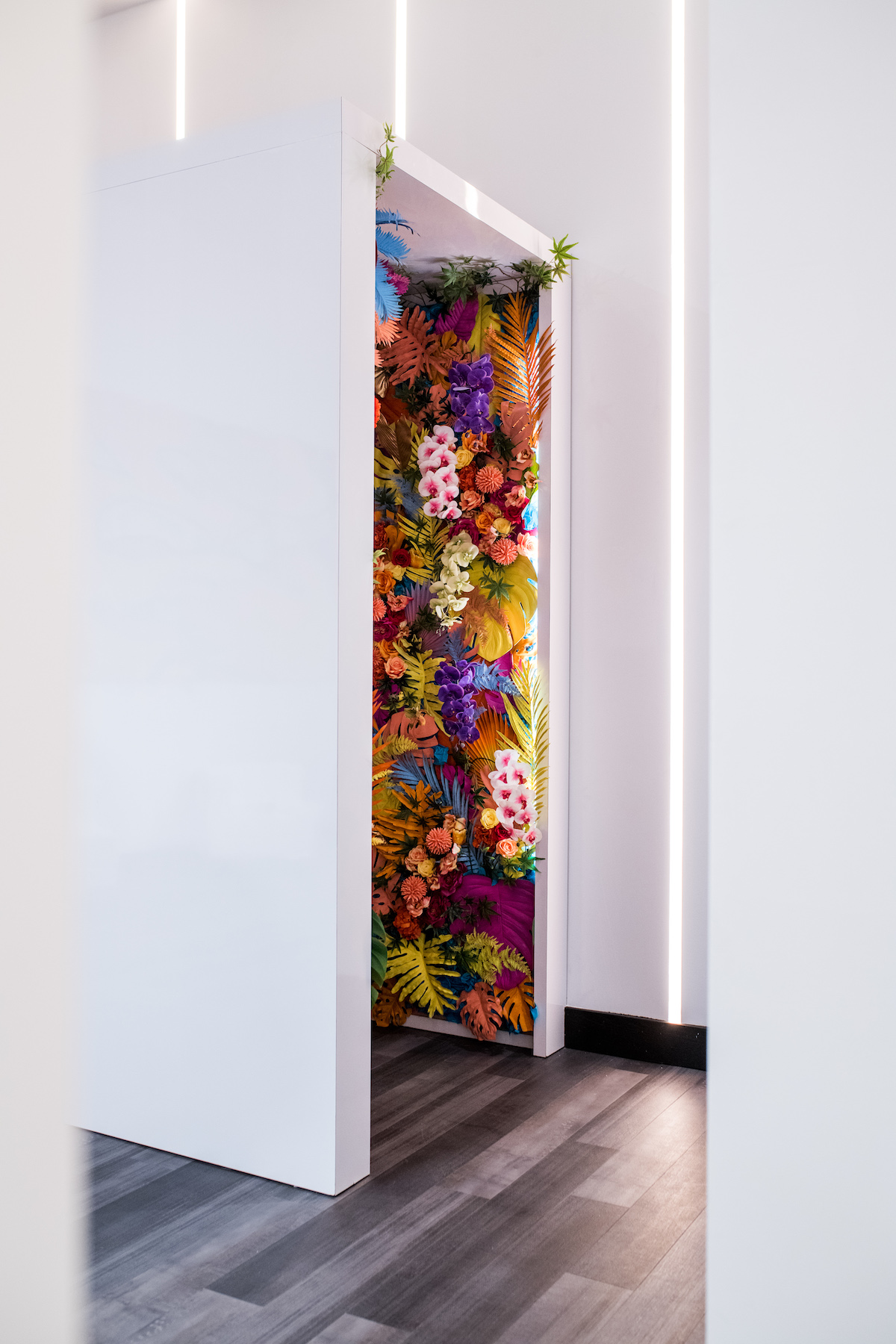 a doorway in a white room revealing a room lined with brightly colored floweres