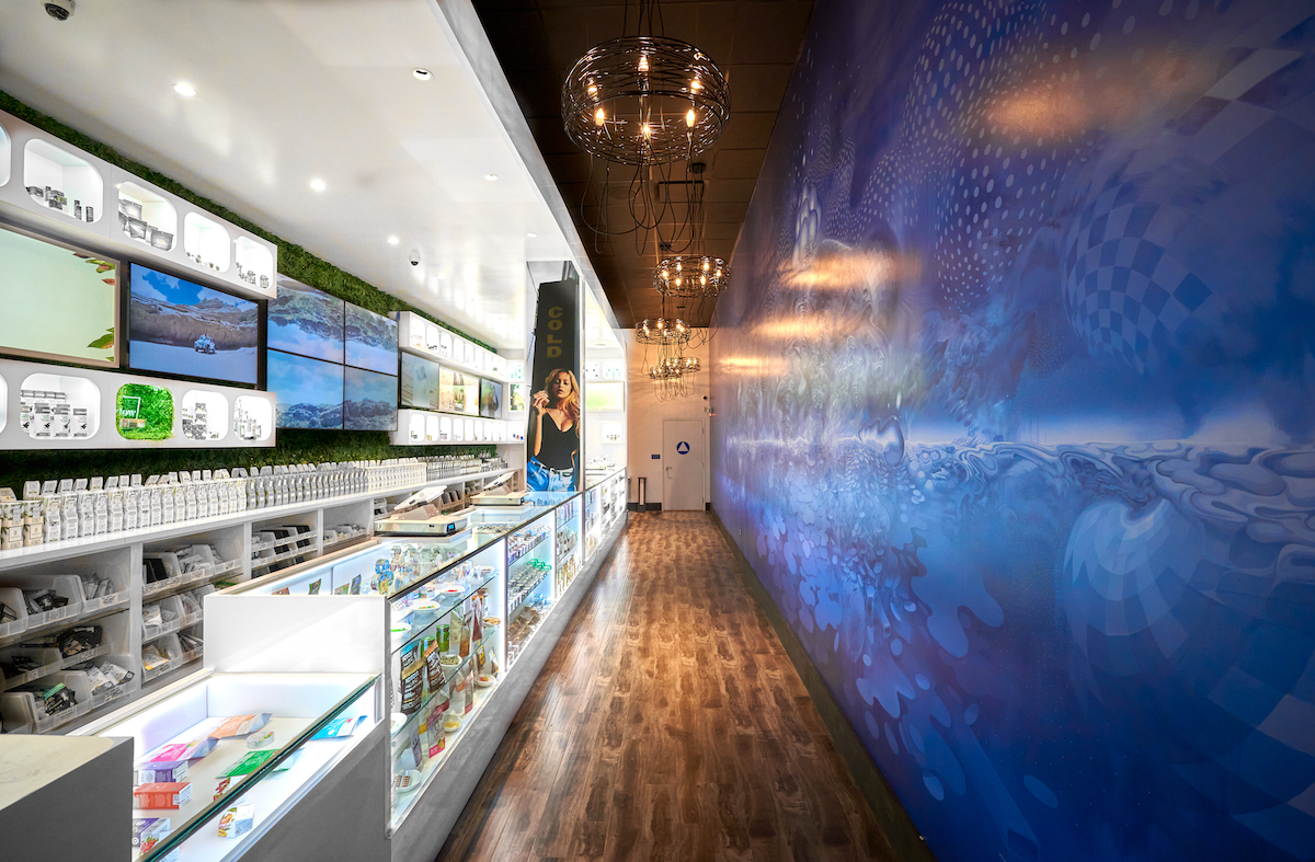 dispensary with one white wall one blue wall and wood flooring and chandeliers hanging from the ceilign