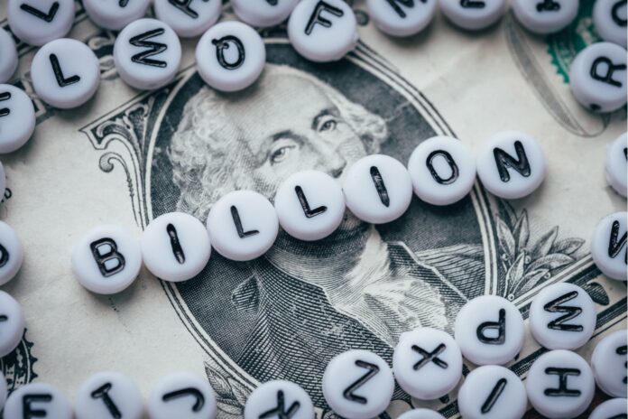 white and black letter beads spelling billion on top of a one dollar bill