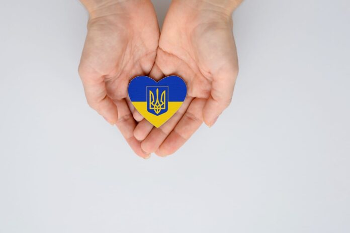 two hands holding a Ukraine flag colored heart