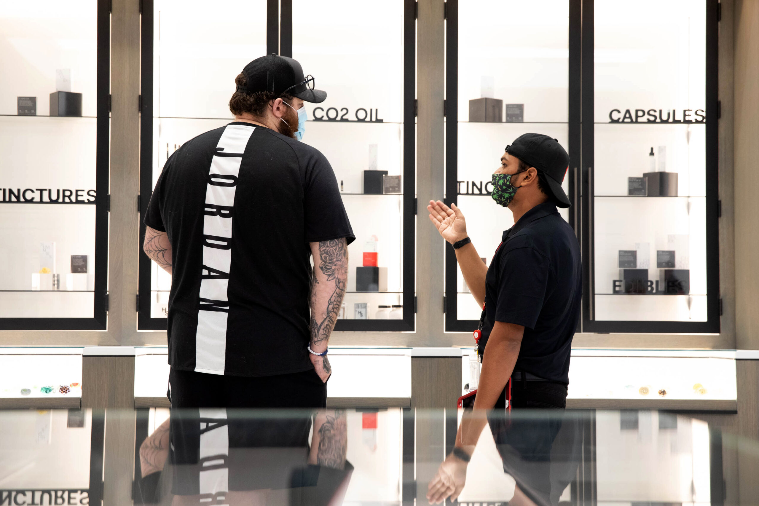two men talking in front of a dispensary display