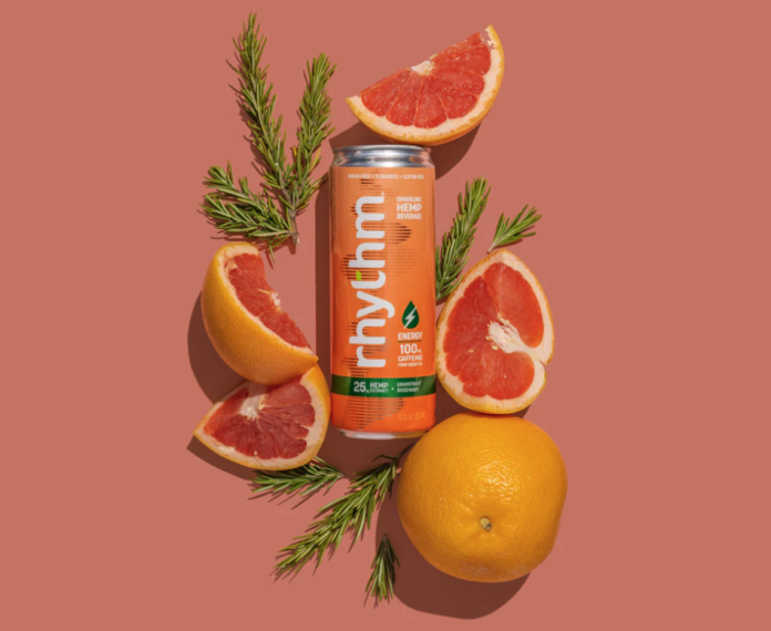 rhythm seltzer coral background with orange rhythm can in center surrounded by blood orange slices and green sprigs of rosemary