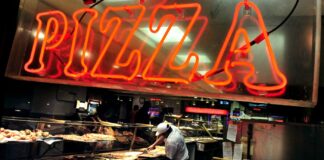 NY Considers Cannabis-Infused Food Sales at Pizzerias and Other Eateries Red neon pizza sign above a man making pizzas at a shop