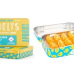Legacy Cannabis Edibles Brand Cheeba Chews Launches Live Rosin-Infused Pâte De Fruit Chew MELTS Cheeba chews melts display image the rectangular metal container is opened revealing the orange edibles inside and another container is placed next to the open container showcasing the yellow and blue label