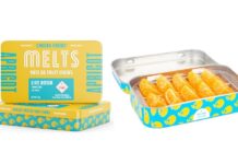 Legacy Cannabis Edibles Brand Cheeba Chews Launches Live Rosin-Infused Pâte De Fruit Chew MELTS Cheeba chews melts display image the rectangular metal container is opened revealing the orange edibles inside and another container is placed next to the open container showcasing the yellow and blue label