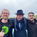 Steve DeAngelo and Andrew DeAngelo Join Harvest Direct’s Advisory Board photo of three men smiling with their arms around one another. The middle man has two long gray braids and is wearing a fedora the man on the left is giving a thumbs up and the man on the right is throwing up a peace sign