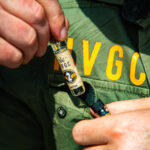 Pre-Rolls Get the SpaceX Treatment with Helmand Valley Growers Company’s Chillums close up photo of someone's hands pulling a HVGC product out of a pocket on a jacket with the letters H V G C printed above the pocket