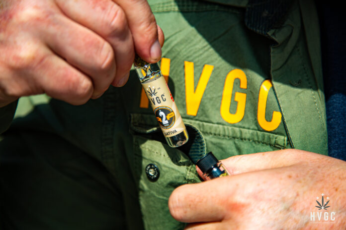 close up photo of someone's hands pulling a HVGC product out of a pocket on a jacket with the letters H V G C printed above the pocket