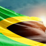 Jamaica: Religion, Culture, and Regulation Jamaica national flag waving in beautiful sky.