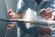 7 Cannabis Schools for Continuing and Professional Education Business planning, E learning concept. Casual business man writing on notebook and working on laptop computer in modern office. Man studying online course via laptop and lecture on notepad.