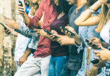 Gen Z Is Changing the Face of Retail Group of multicultural friends using smartphone outdoors - People hands addicted by mobile smart phone - Technology concept with connected men and women - Shallow depth of field on vintage filter tone