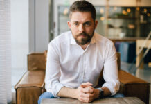 How to Acquire New Customers and Keep the Ones You Have man with beard in white business shirt with arms on table in brown leather chair kyle sherman flowhub