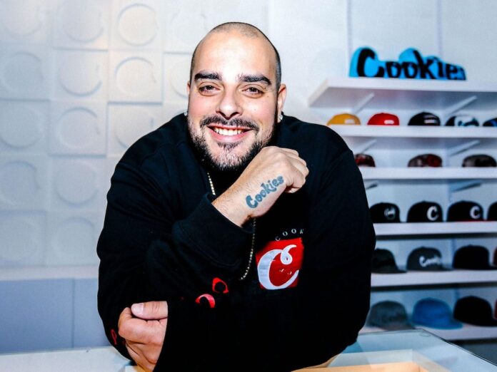 photo of rapper berner showcasing his cookies tattoo and wearing a big smile with a thick mustache and a bald head