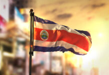 Costa Rican President Announces Recreational Cannabis Legislation Costa Rica Flag Against City Blurred Background At Sunrise Backlight 3D Rendering