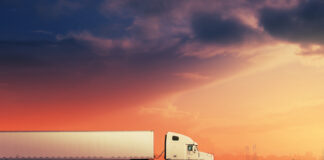 New Jersey Introduces Interstate Cannabis Commerce Bill White freight truck driving on freeway road under red sunset sky.
