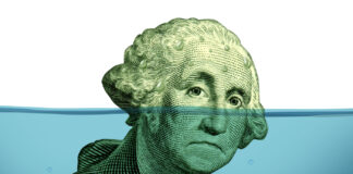 Is There a Solution to the Cash Crunch? Debt problems keeping your financial head above water represented by a drowning George Washington portrait sinking in blue water as a symbol of urgent business and money management failure and defeat.