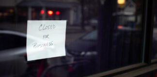 Trulieve Shutters California, Massachusetts Operations Hand written "Closed for Business" sign in the dark window of a shut down business