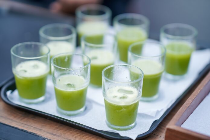 GREEN COLOR AVOCADO SMOOTHIE JUICE HALF GLASS FULL ON A TRAY