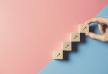 4 Things You Can Do to Move Your Business Forward Right Now Business concept growth success process, Close up man hand arranging wood block stacking as step stair on paper blue and pink background, copy space.