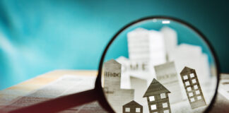 How to Navigate Retail Real Estate Magnifying glass in front of an open newspaper with paper houses. Concept of rent, search, purchase real estate.