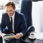 Defying Digital: The Resilience of Print Advertising in the Modern Age Businessman in suit reading magazine with morning coffee