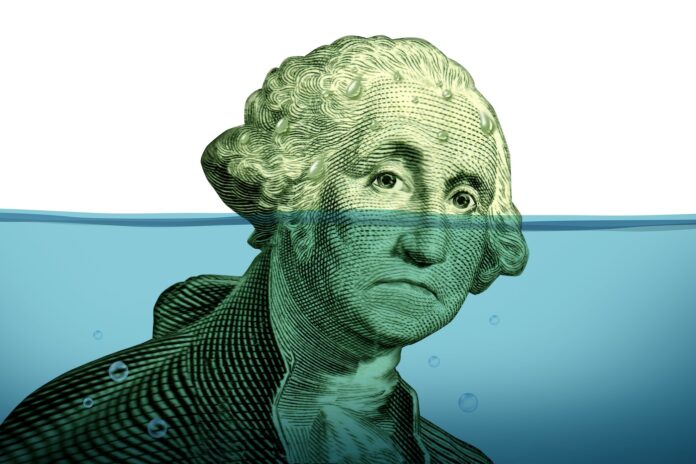 Debt problems keeping your financial head above water represented by a drowning George Washington portrait sinking in blue water as a symbol of urgent business and money management failure and defeat.