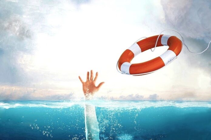 Throwing a life rope buoy to a drowning person holding a hand above water.