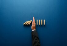 Thrive to Survive with Risk Mitigation Strategies for 2024 Top,View,Of,Businessman,Hand,Stopping,Falling,Dominos,In,A