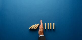 Thrive to Survive with Risk Mitigation Strategies for 2024 Top,View,Of,Businessman,Hand,Stopping,Falling,Dominos,In,A