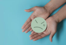 Americans Distrust Big Tobacco, Alcohol, and Pharma for Cannabis Policy two open hands holding a frowning paper face