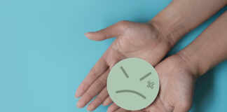 Americans Distrust Big Tobacco, Alcohol, and Pharma for Cannabis Policy two open hands holding a frowning paper face