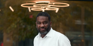 Opinion: Power, History, and Luxury Monko CEO Terrence White in a white business shirt standing in front of a dispensary window with lights above his head Captured by Immanuel Powell Captured by Immanuel Powell