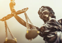 The Hidden Risks of Failing to Comply with GMP Close up of metal scales of justice, lady justice with golden lighting